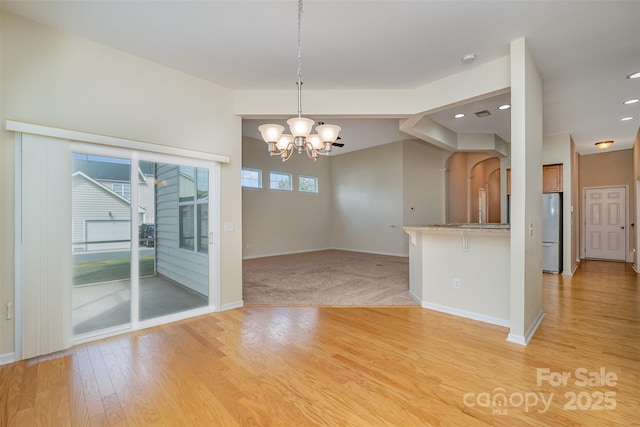 interior space with hanging light fixtures, light wood-type flooring, kitchen peninsula, and white fridge