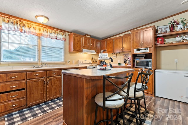 kitchen with dark hardwood / wood-style flooring, a kitchen island, a textured ceiling, vaulted ceiling, and fridge