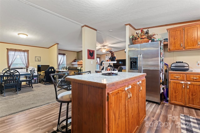 kitchen featuring a kitchen island, stainless steel refrigerator with ice dispenser, dark hardwood / wood-style floors, and a textured ceiling