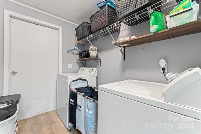 laundry room featuring light hardwood / wood-style floors, a textured ceiling, and washing machine and dryer