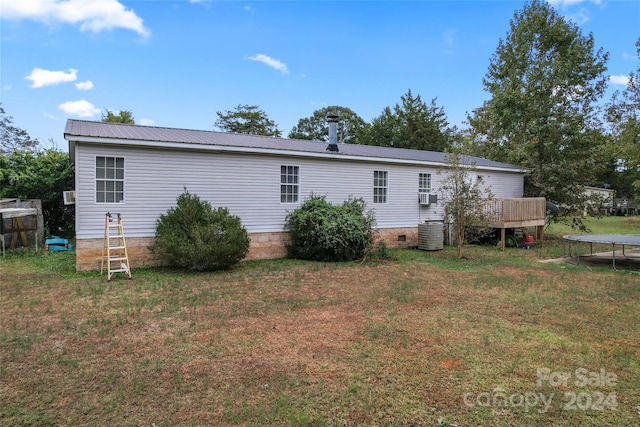 back of house featuring central air condition unit, a deck, and a lawn