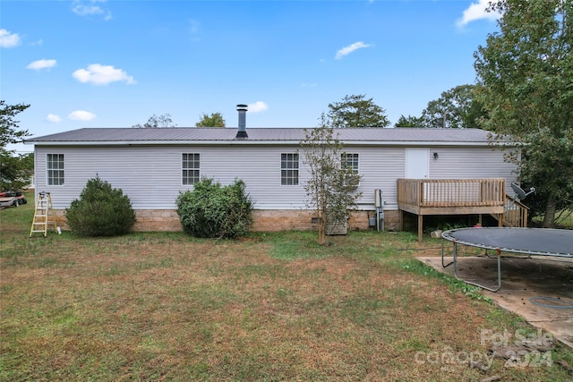 back of property with a wooden deck and a lawn