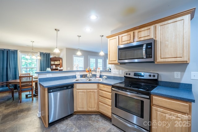 kitchen with light brown cabinets, a sink, dark countertops, appliances with stainless steel finishes, and a peninsula