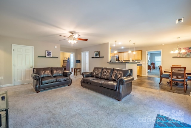 living area with visible vents, ceiling fan with notable chandelier, and baseboards