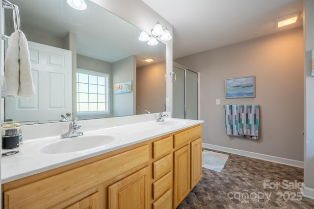 bathroom with double vanity, an enclosed shower, baseboards, and a sink