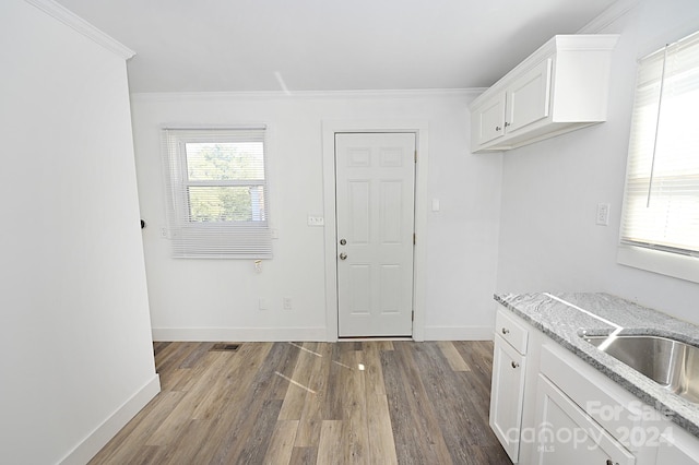 kitchen featuring crown molding, white cabinets, hardwood / wood-style flooring, and light stone countertops