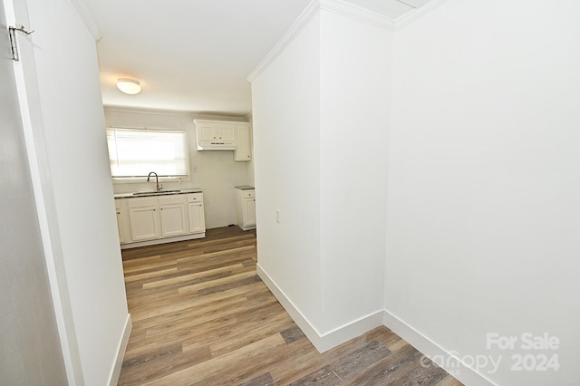 hall with ornamental molding, hardwood / wood-style floors, and sink