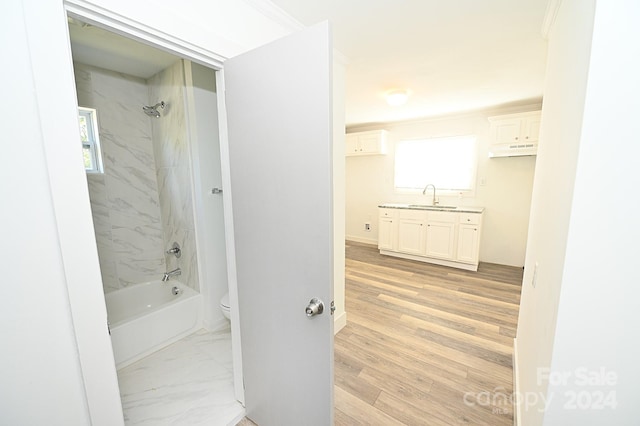 full bathroom with wood-type flooring, toilet, ornamental molding, vanity, and tiled shower / bath combo