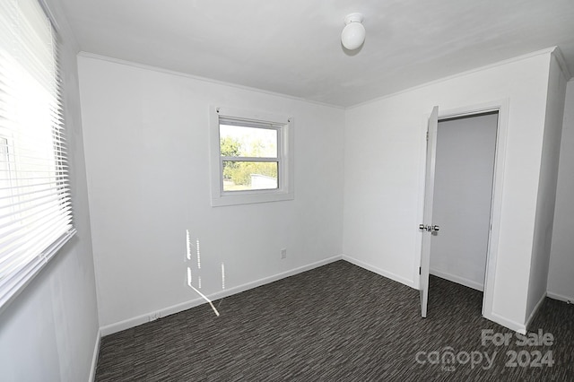 unfurnished bedroom featuring ornamental molding and dark carpet