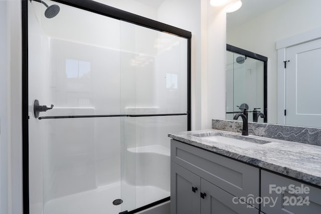 bathroom featuring a shower with shower door and vanity