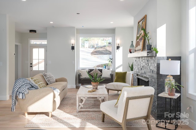 living room with light hardwood / wood-style flooring and a stone fireplace