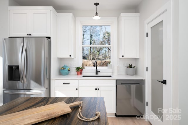 kitchen with white cabinets, sink, decorative backsplash, appliances with stainless steel finishes, and decorative light fixtures