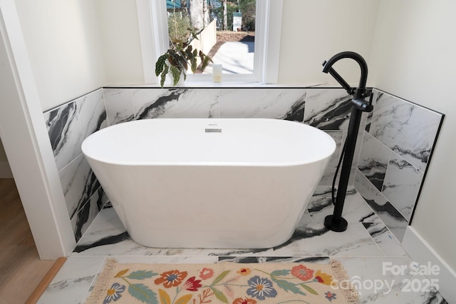 bathroom featuring a tub to relax in and tile walls