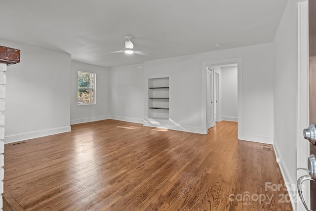 unfurnished room with hardwood / wood-style flooring, built in features, and ceiling fan