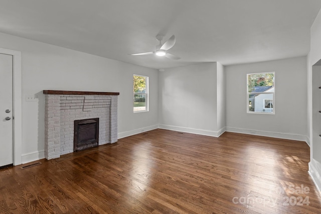 unfurnished living room with a fireplace, dark hardwood / wood-style floors, plenty of natural light, and ceiling fan