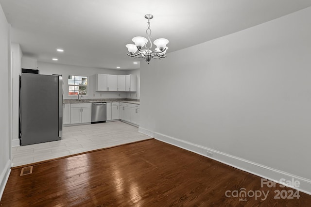 kitchen featuring light hardwood / wood-style flooring, hanging light fixtures, stainless steel appliances, an inviting chandelier, and white cabinets