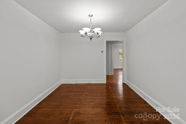 unfurnished dining area with dark wood-type flooring and a chandelier