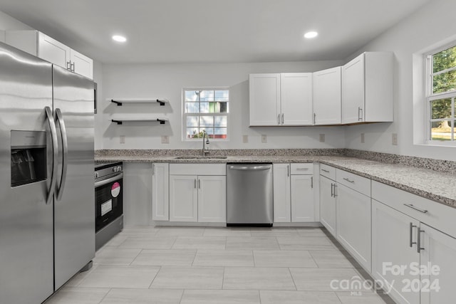 kitchen featuring white cabinetry, light stone counters, stainless steel appliances, and sink