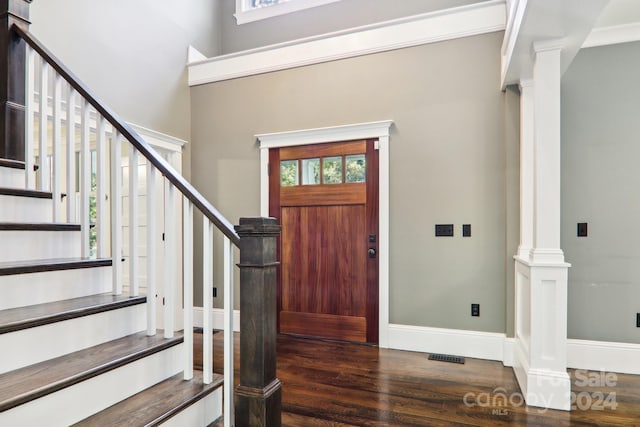 foyer entrance featuring crown molding, dark hardwood / wood-style floors, and decorative columns