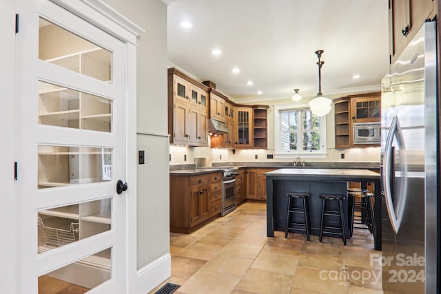 kitchen with appliances with stainless steel finishes, sink, a breakfast bar, pendant lighting, and light tile patterned floors