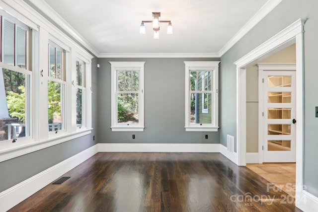 spare room featuring crown molding, a healthy amount of sunlight, and dark hardwood / wood-style flooring