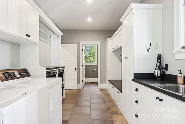 laundry room with sink, washing machine and clothes dryer, light tile patterned floors, and cabinets