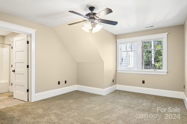 additional living space featuring ceiling fan, vaulted ceiling, and light colored carpet