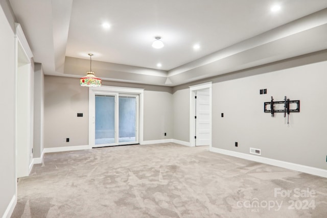 spare room featuring light colored carpet and a raised ceiling