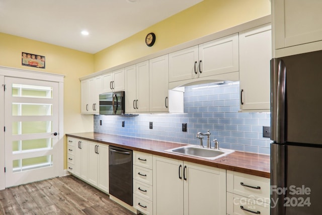 kitchen with stainless steel appliances, backsplash, sink, light wood-type flooring, and butcher block countertops