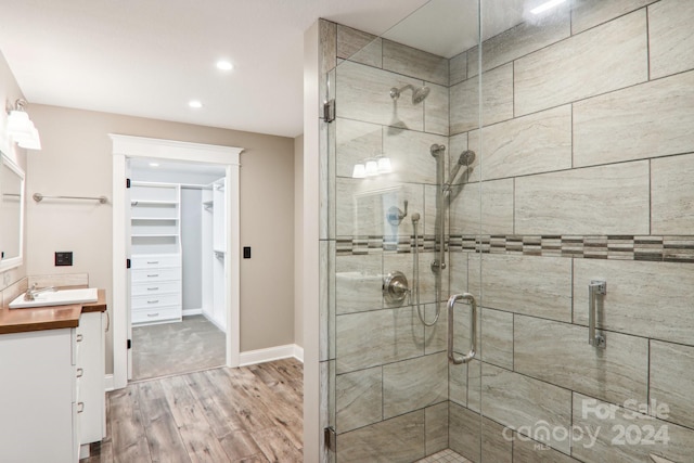 bathroom with a shower with door, vanity, and hardwood / wood-style floors