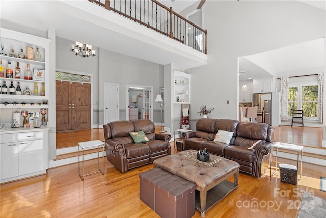 living room featuring light hardwood / wood-style floors, a chandelier, and high vaulted ceiling