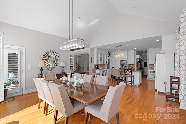 dining room with ornate columns, high vaulted ceiling, and light wood-type flooring