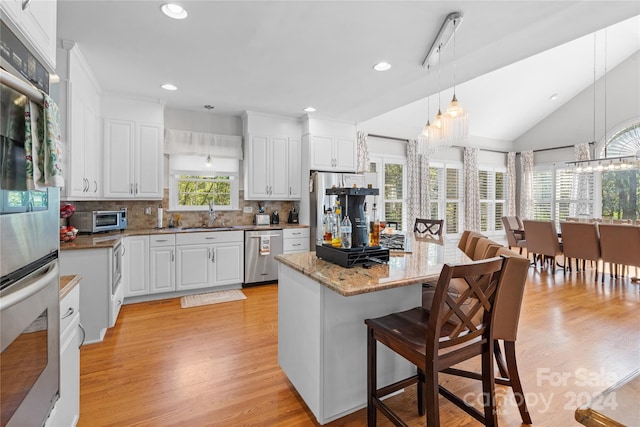 kitchen with appliances with stainless steel finishes, white cabinets, and a wealth of natural light