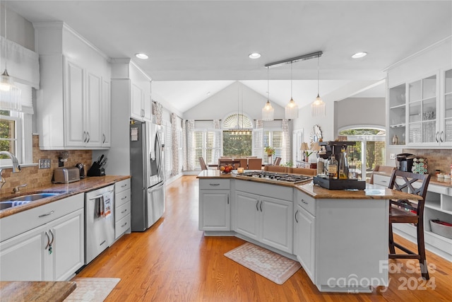 kitchen featuring appliances with stainless steel finishes, white cabinetry, a kitchen bar, and plenty of natural light