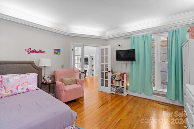 bedroom featuring french doors, multiple windows, hardwood / wood-style flooring, and crown molding