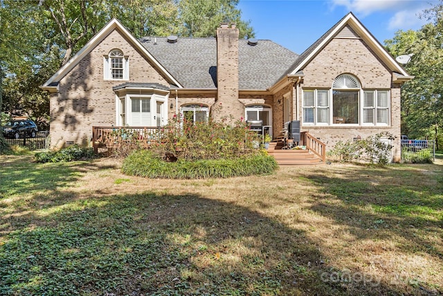 rear view of property with a wooden deck and a lawn