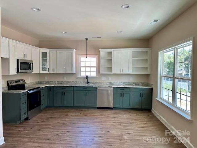 kitchen featuring white cabinets, appliances with stainless steel finishes, sink, light hardwood / wood-style floors, and decorative light fixtures