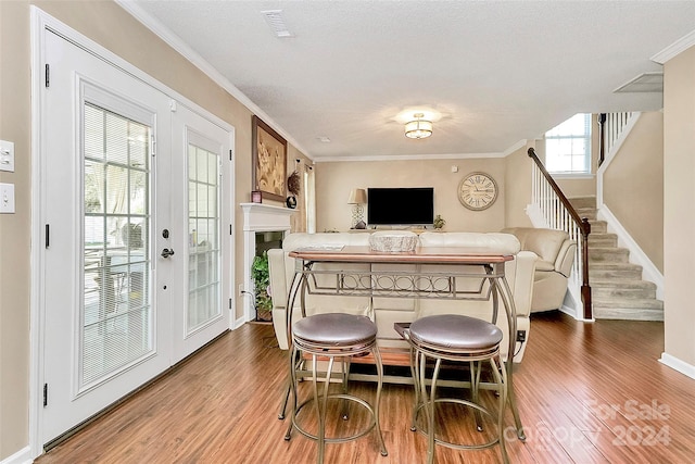 dining area featuring bar area, french doors, a textured ceiling, hardwood / wood-style floors, and ornamental molding