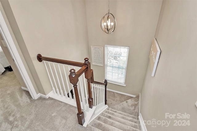 staircase featuring carpet floors and a chandelier