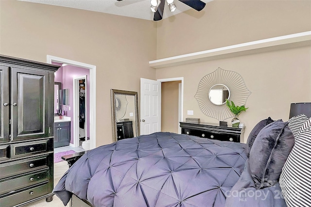 bedroom featuring ceiling fan, a towering ceiling, ensuite bathroom, and light colored carpet