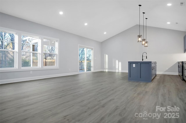 unfurnished living room with baseboards, lofted ceiling, wood finished floors, a sink, and recessed lighting