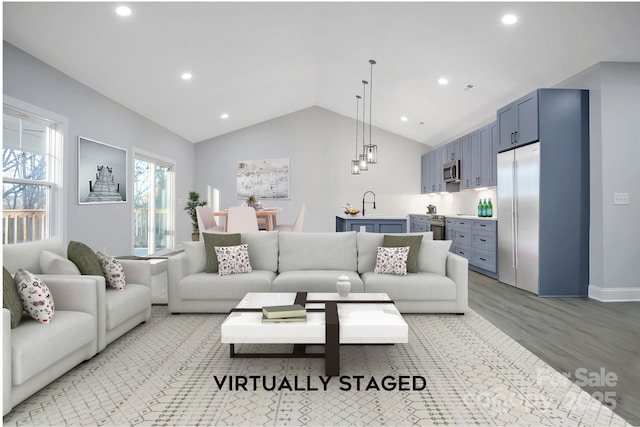 living room with lofted ceiling, sink, and light wood-type flooring