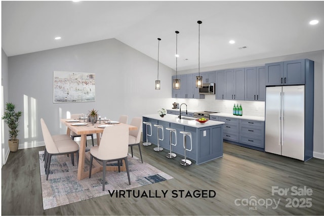 kitchen with stainless steel appliances, lofted ceiling, light countertops, hanging light fixtures, and a sink