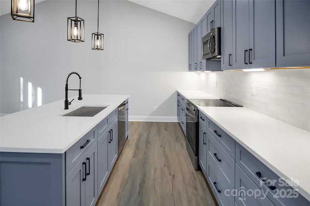 kitchen with sink, a center island with sink, light wood-type flooring, pendant lighting, and stainless steel appliances