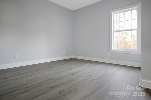 unfurnished room with baseboards and dark wood finished floors