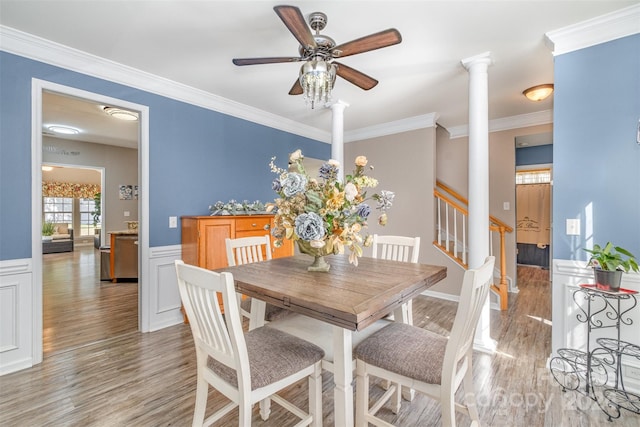 dining area featuring crown molding, light hardwood / wood-style flooring, ornate columns, and ceiling fan