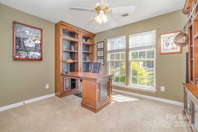 office space with baseboards, a ceiling fan, visible vents, and light carpet