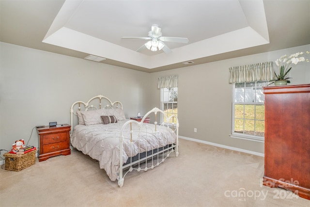 bedroom with visible vents, baseboards, a tray ceiling, and carpet