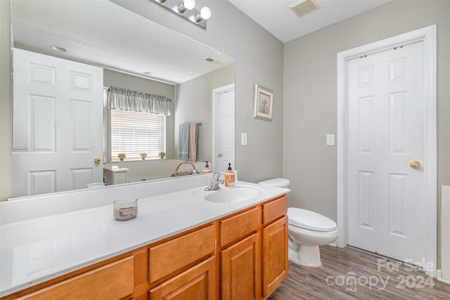 bathroom featuring wood finished floors, visible vents, vanity, and toilet