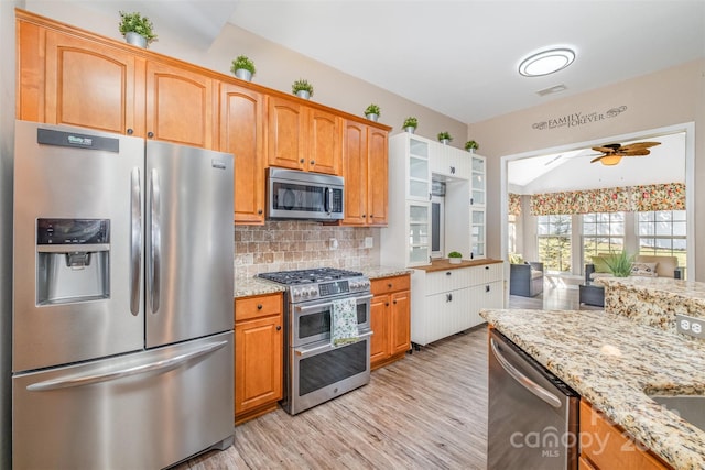 kitchen featuring light hardwood / wood-style flooring, ceiling fan, appliances with stainless steel finishes, light stone counters, and tasteful backsplash